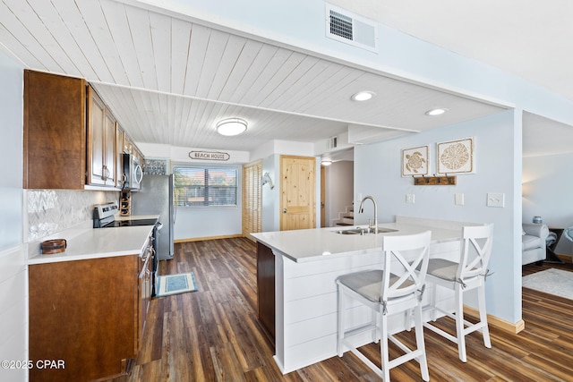 kitchen with sink, a kitchen bar, dark hardwood / wood-style floors, decorative backsplash, and stainless steel appliances