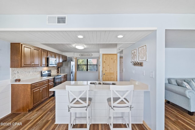 kitchen with a kitchen bar, tasteful backsplash, sink, stainless steel appliances, and dark hardwood / wood-style floors