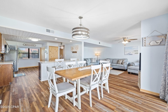 dining room with wood-type flooring and ceiling fan with notable chandelier