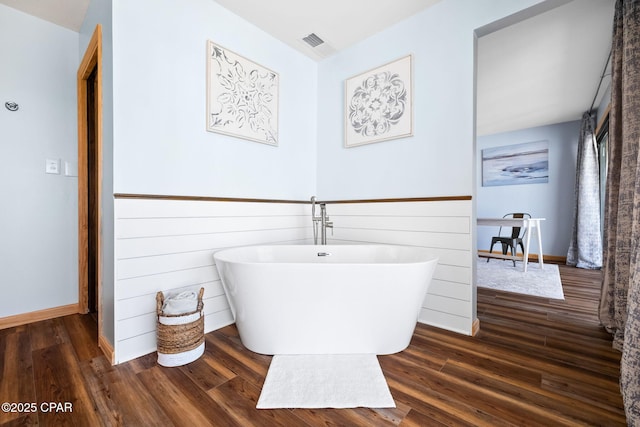 bathroom with hardwood / wood-style floors and a bath