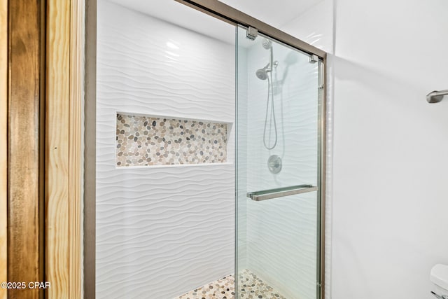 bathroom featuring a shower with door and toilet