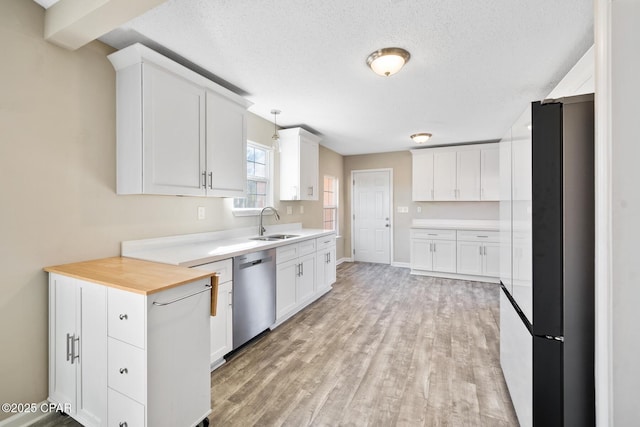 kitchen with a textured ceiling, stainless steel appliances, sink, pendant lighting, and white cabinets