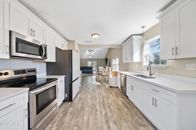 kitchen with white cabinetry, ceiling fan, sink, hanging light fixtures, and stainless steel appliances