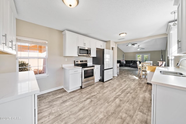 kitchen featuring sink, white cabinets, stainless steel appliances, and lofted ceiling