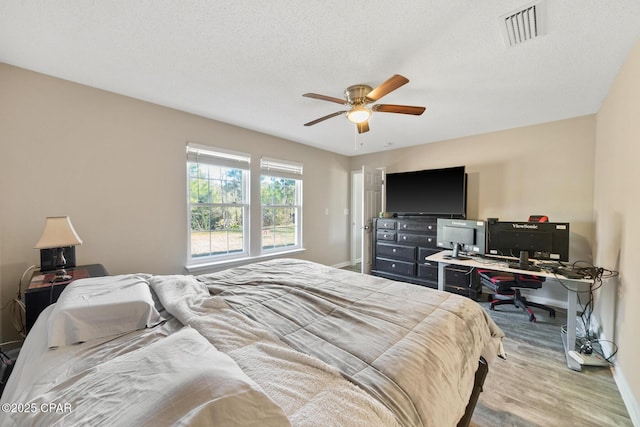 bedroom featuring ceiling fan, light hardwood / wood-style flooring, and a textured ceiling