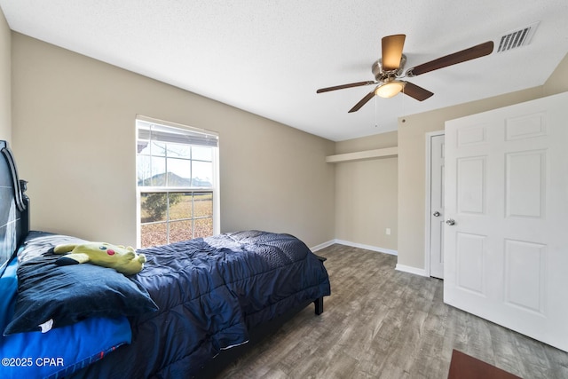 bedroom featuring wood-type flooring, a textured ceiling, and ceiling fan