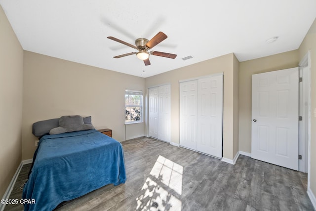 bedroom featuring two closets, hardwood / wood-style flooring, and ceiling fan