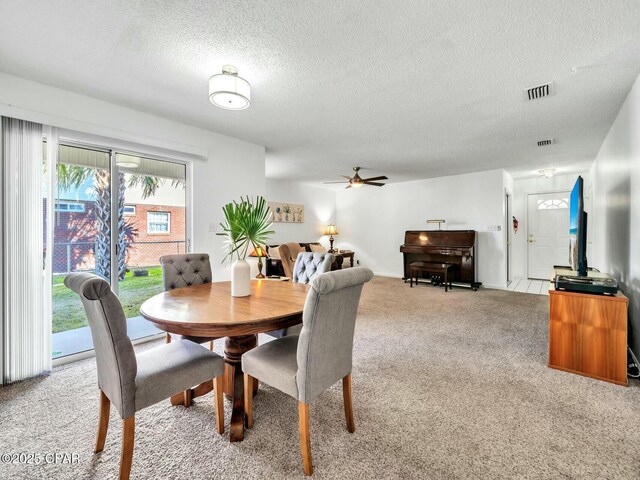 carpeted dining room with ceiling fan and a textured ceiling