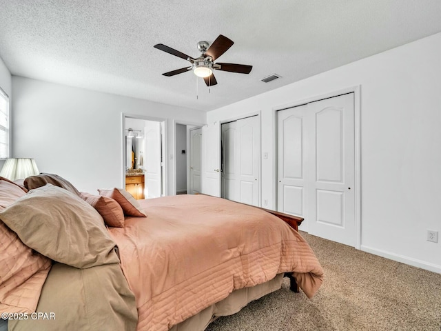 bedroom featuring a textured ceiling, carpet flooring, two closets, and ceiling fan