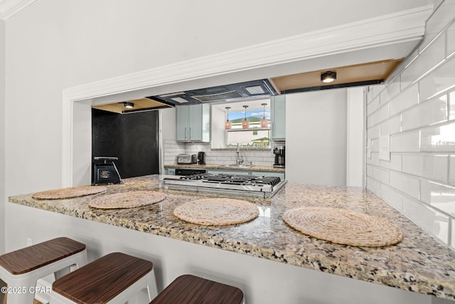 kitchen featuring a breakfast bar, sink, tasteful backsplash, kitchen peninsula, and stainless steel gas cooktop