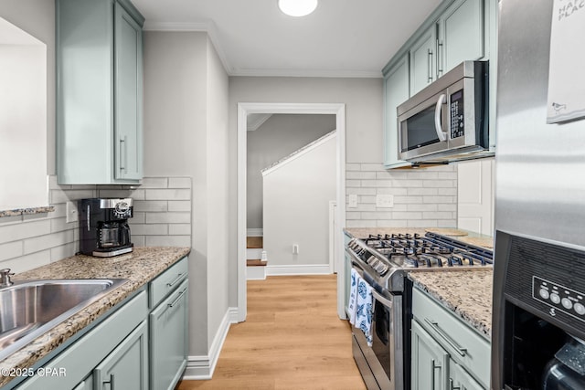 kitchen with decorative backsplash, light stone countertops, crown molding, and appliances with stainless steel finishes