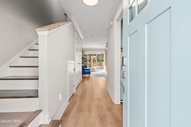 foyer with light wood-type flooring and crown molding