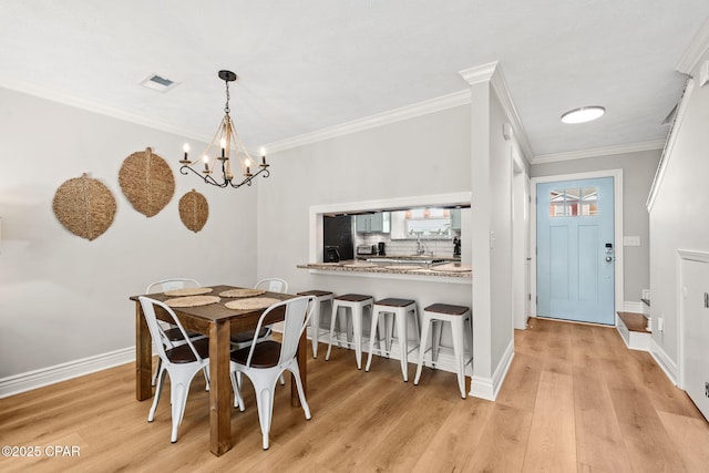 dining area featuring light wood-type flooring, crown molding, and a chandelier