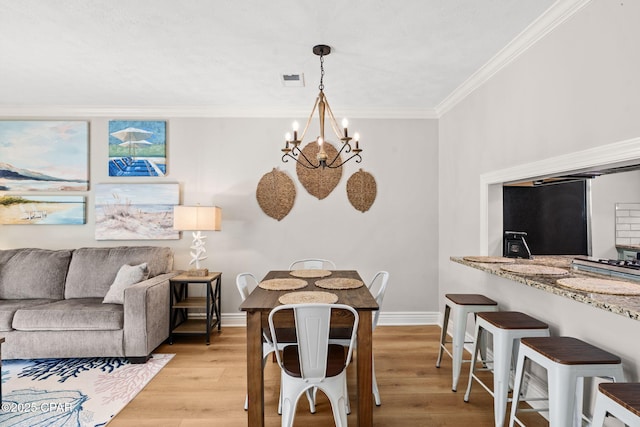 dining space with light wood-type flooring, an inviting chandelier, and ornamental molding