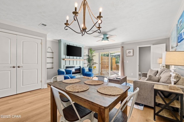 dining space featuring a textured ceiling, ceiling fan with notable chandelier, crown molding, and light hardwood / wood-style flooring