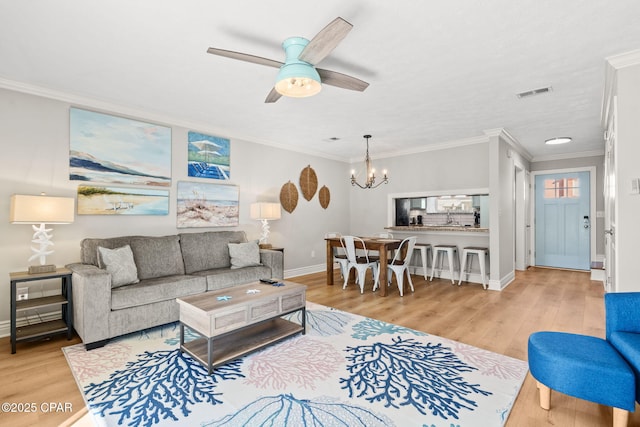 living room featuring ceiling fan with notable chandelier, light wood-type flooring, and crown molding