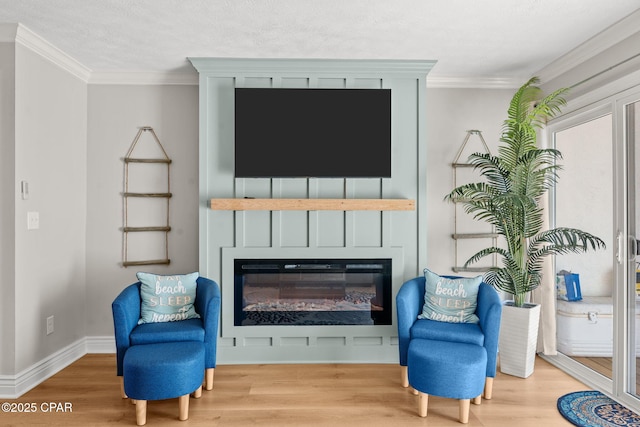 sitting room with a textured ceiling, a large fireplace, wood-type flooring, and crown molding