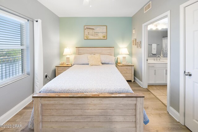 bedroom featuring sink, light hardwood / wood-style floors, and ensuite bath