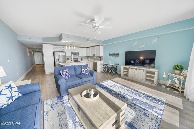 living room with ceiling fan and light wood-type flooring