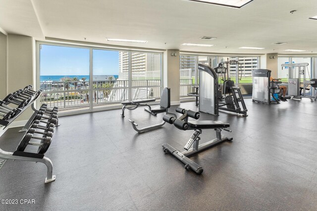 exercise room featuring expansive windows and a water view