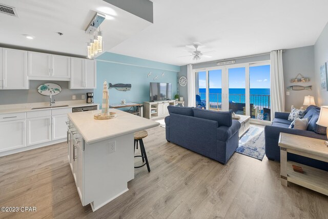 kitchen featuring light wood-type flooring, a breakfast bar, white cabinets, and a kitchen island