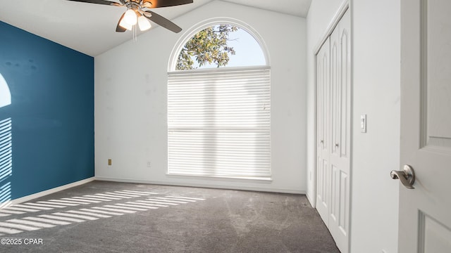 carpeted spare room with ceiling fan and vaulted ceiling