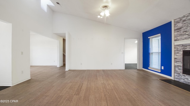 unfurnished living room with a fireplace, wood-type flooring, vaulted ceiling, and ceiling fan