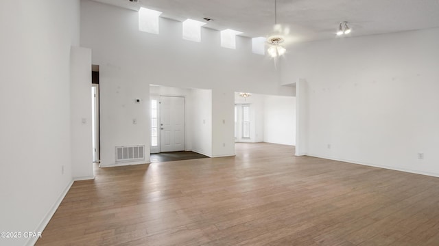 unfurnished living room featuring wood-type flooring and a high ceiling