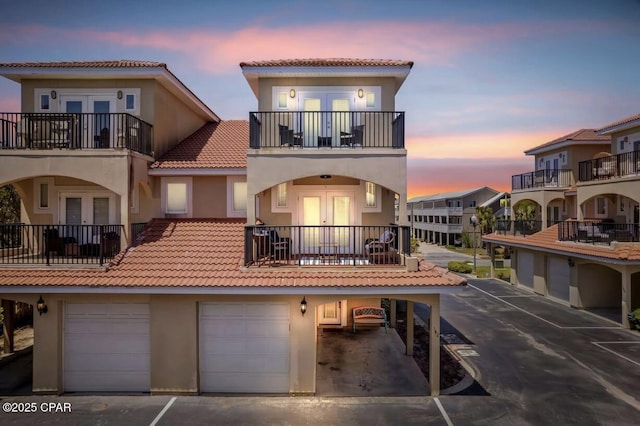 back house at dusk with a garage and french doors