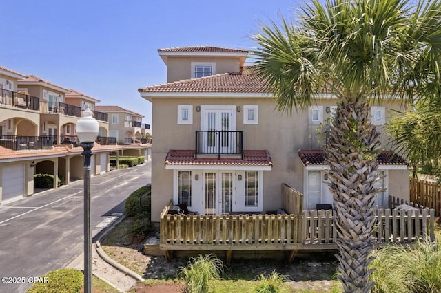 rear view of property featuring a balcony and french doors