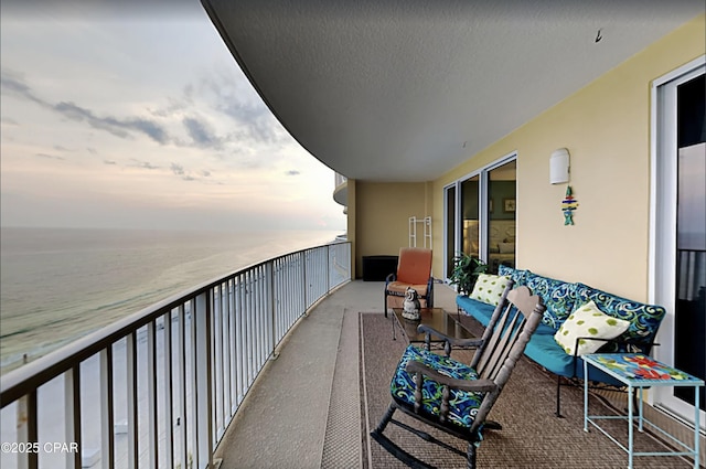 balcony at dusk featuring a water view