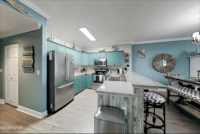 kitchen with sink, a breakfast bar area, ornamental molding, appliances with stainless steel finishes, and kitchen peninsula