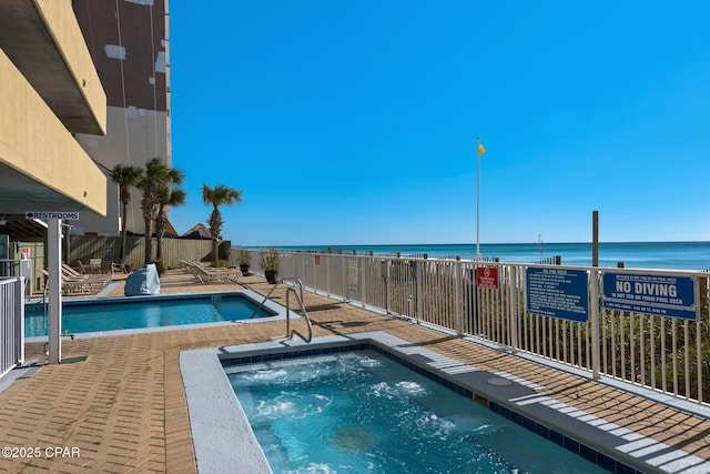 view of swimming pool with a community hot tub and a water view