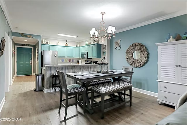 dining space with a notable chandelier, ornamental molding, and light wood-type flooring