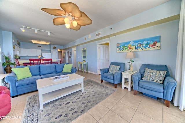 living room featuring light tile patterned floors, a textured ceiling, track lighting, and ceiling fan