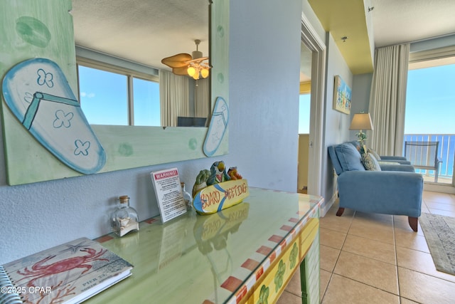 tiled dining area featuring a textured ceiling, a water view, and ceiling fan