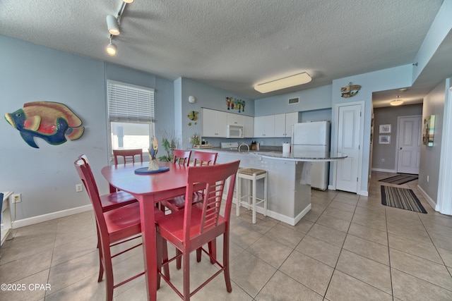 dining area featuring a textured ceiling, light tile patterned flooring, baseboards, and visible vents