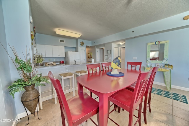 dining space featuring a textured ceiling, light tile patterned floors, baseboards, and visible vents