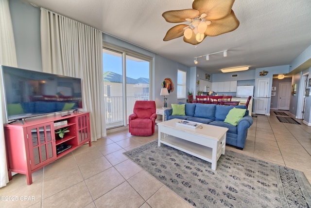 living room featuring a textured ceiling, rail lighting, ceiling fan, and light tile patterned flooring