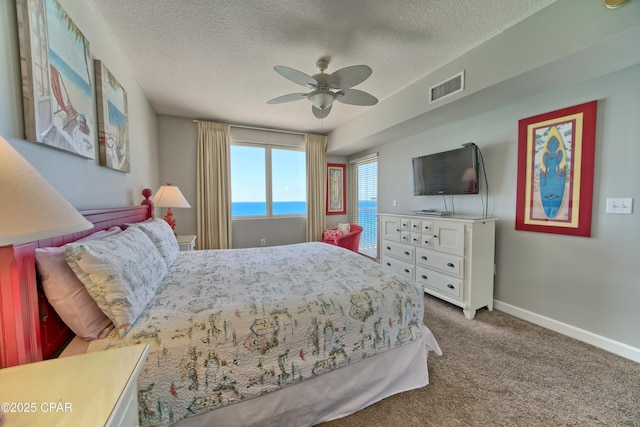 carpeted bedroom with a textured ceiling, ceiling fan, baseboards, and visible vents