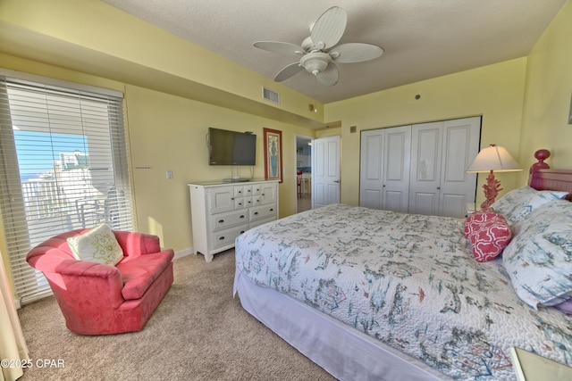 carpeted bedroom with ceiling fan, a closet, and a textured ceiling