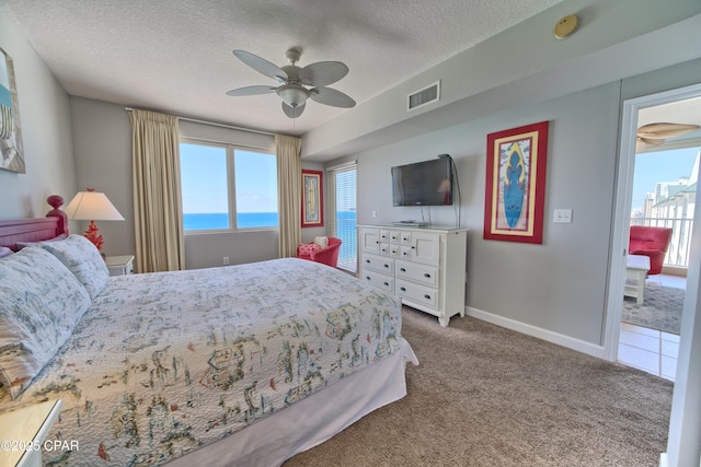 carpeted bedroom featuring visible vents, baseboards, a ceiling fan, and a textured ceiling