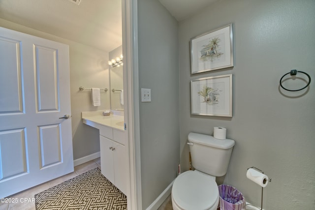 bathroom featuring tile patterned flooring, vanity, baseboards, and toilet