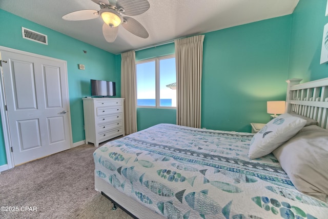 carpeted bedroom featuring ceiling fan and a textured ceiling