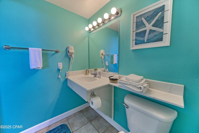 bathroom with toilet, sink, and tile patterned flooring