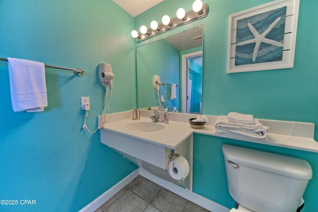 bathroom featuring visible vents, toilet, a sink, tile patterned floors, and baseboards