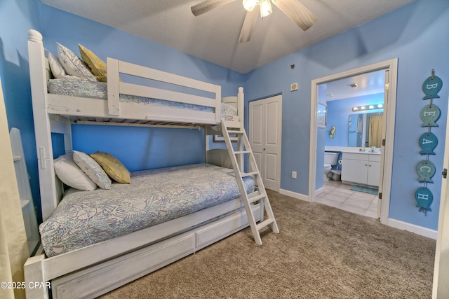 carpeted bedroom with ceiling fan, a textured ceiling, connected bathroom, and a closet