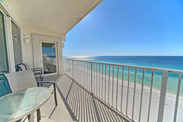 balcony with a water view and a view of the beach