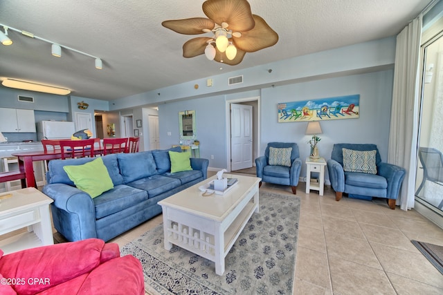 living area with visible vents, ceiling fan, light tile patterned floors, and a textured ceiling