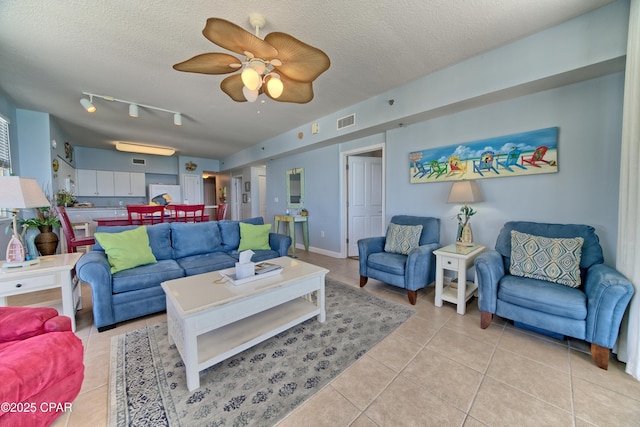 living room featuring visible vents, a ceiling fan, light tile patterned floors, and a textured ceiling
